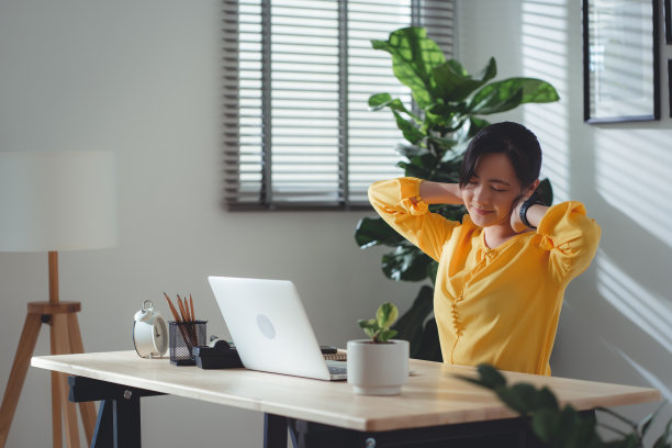 亚洲女性坐在家里办公室，患有办公室综合症。图片下载
