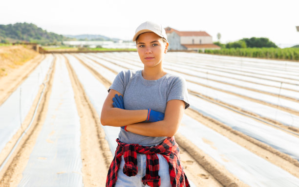 微笑的女孩农场工人站在种植覆盖聚乙烯覆盖物图片下载