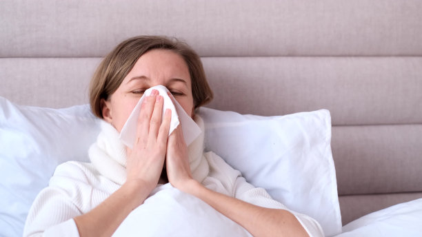 一个感冒的女人躺在家里的床上。流感的概念。图片下载