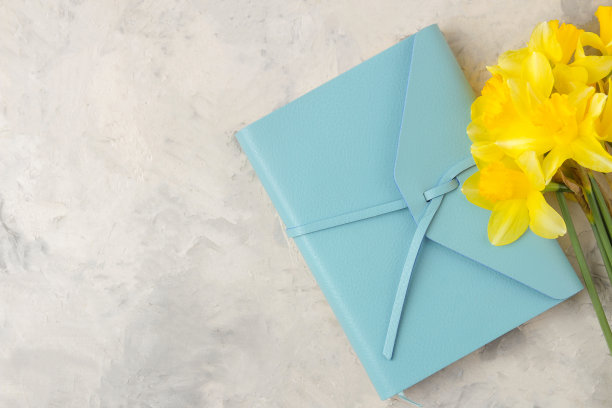 一束春天的花水仙花和一个蓝色的记事本在浅色的背景图片下载