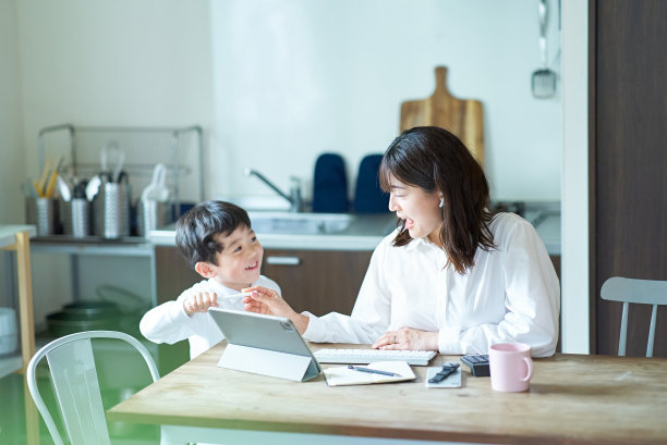 一位神情疲惫的母亲一边工作一边被孩子打扰图片下载