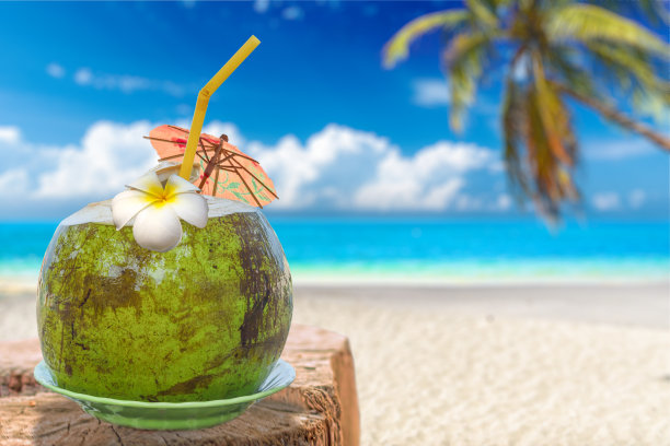 新鲜的椰子坚果饮料与模糊的海滩和日落的背景图片下载