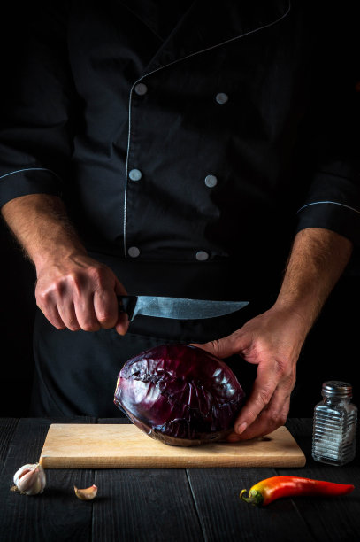 厨师正在用刀切红卷心菜。在餐厅厨房做蔬菜沙拉。蔬菜饮食理念图片下载