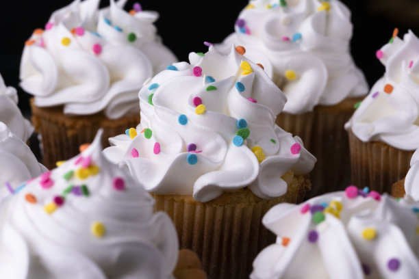 蓬松的香草纸杯蛋糕，黑色背景上有蛋白酥皮和烤焦糖。图片下载