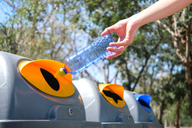 请把塑料瓶扔到垃圾桶里。人们将垃圾分类处理，如可回收的塑料垃圾。环境的概念图片下载