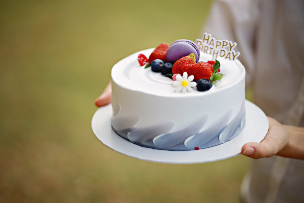 在户外公园野餐时，女子手持蛋糕庆祝生日图片下载