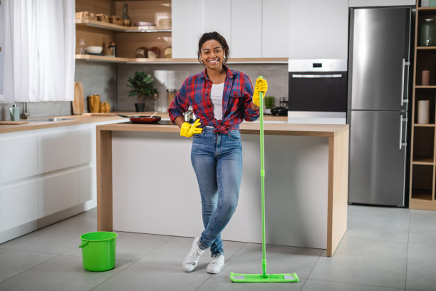 微笑的千禧非洲裔美国妇女家庭主妇橡胶手套与拖把洗地板，享受清洁图片下载