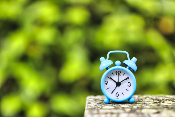 浅蓝色闹钟和绿色模糊背景图片下载