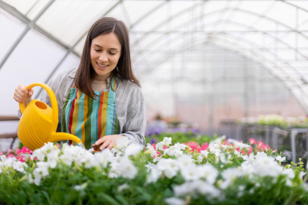 欢快的女花匠将新鲜的水浇在五彩缤纷的花瓣花坛上图片下载