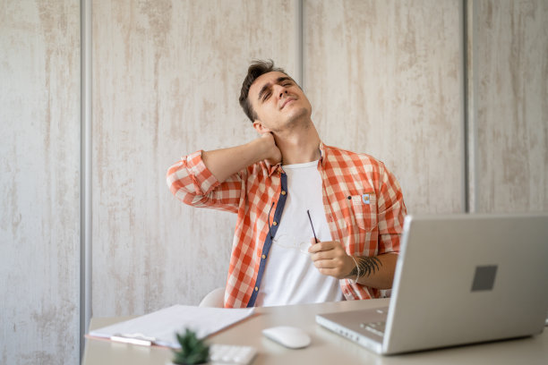 年轻男子在工作时，坐在办公桌前，颈部疼痛图片下载