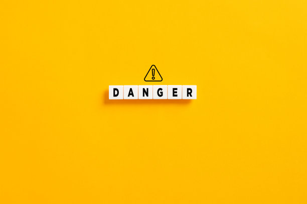 黄色背景上的白色字母块与单词危险和警告标志。风险和危险的概念。图片下载