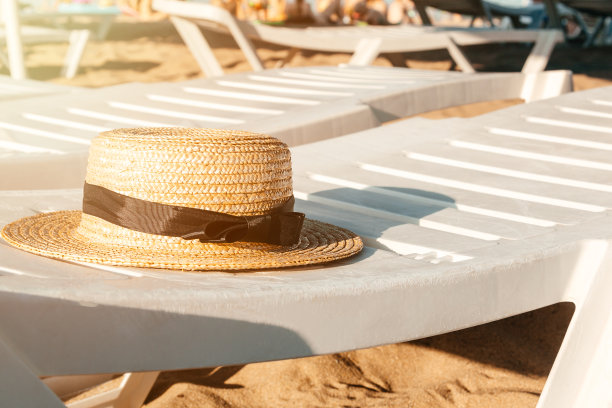 沙滩上白色甲板上的草帽。海边的躺椅。暑假背景图片下载