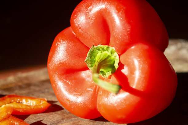 红色灯笼椒放在木板上。鲜亮健康的蔬菜。一张在黑暗中木板上红皮灯笼椒的照片。图片下载