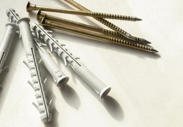 销子和螺丝放在浅色背景上。施工设备。在肮脏的白色桌子上是黄色的螺丝和灰色的销子。图片下载