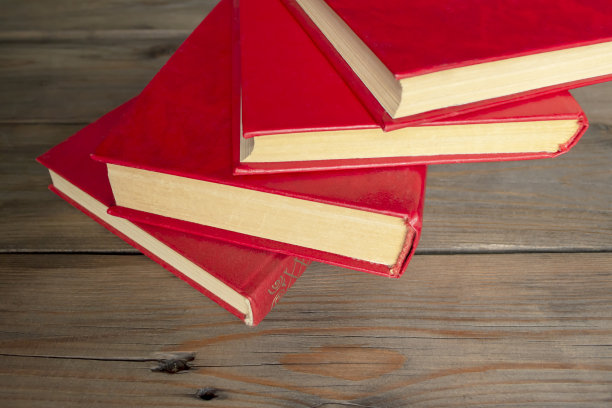 有红皮的书放在木桌上。在木制背景上放着几本红色封面的书。中学和大学的教科书。图片下载