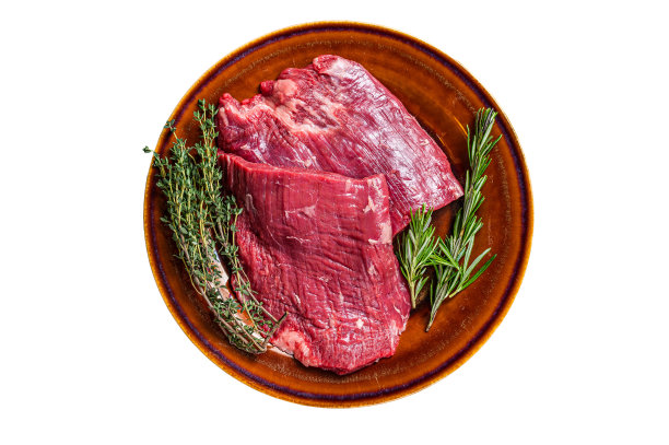 两份生牛肉排，配以香草，放在质朴的盘子里。孤立在白色背景上。图片下载