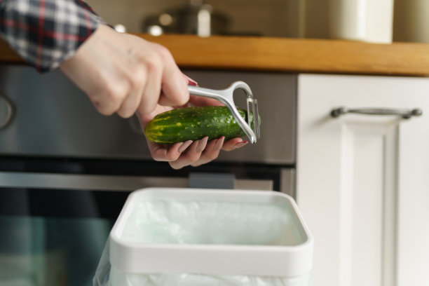 一名妇女在堆肥箱里剥黄瓜皮并回收利用。女性将有机食品垃圾扔进博卡什容器进行发酵图片下载