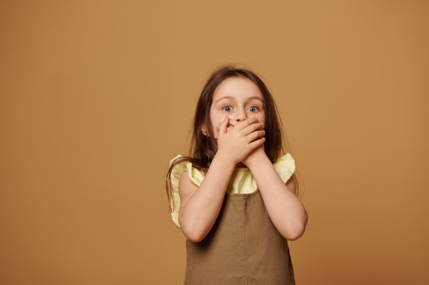 受惊的小女孩用手捂住嘴。儿童的权利。童年的恐惧。儿童保护概念图片下载