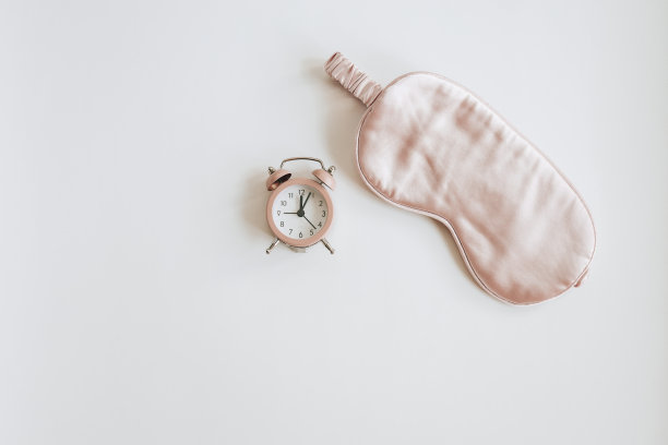 粉色闹钟和白色背景的睡眠面具图片下载