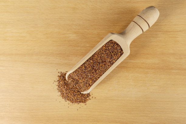 路易波士茶中号切成木勺放在木板上。拉丁文Aspalathus linearis中的Rooibos。赫伯特。花草茶。食品成分。前视图。图片下载