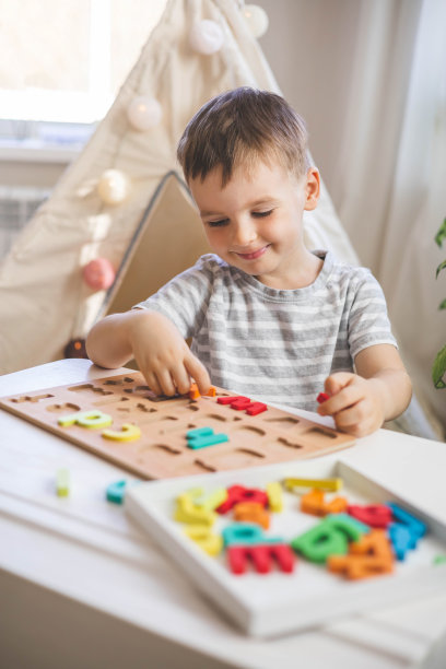 男孩玩木制环保字母板在桌面视图智力游戏图片下载
