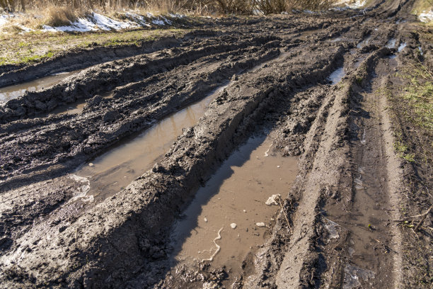 肮脏无法通行的道路。秋天森林里的越野赛道。秋天泥泞道路上深深的车辙。雨天潮湿泥泞的乡村道路在春天的山区破碎的乡村道路，有许多泥泞的水坑图片下载