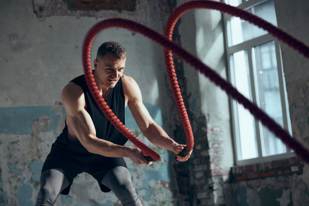 竞争的准备。年轻的运动男子的肖像，强壮，适合，肌肉的身体训练与战斗绳索室内。运动生活方式的概念图片下载