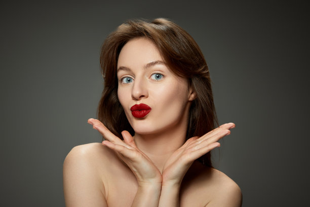 年轻迷人的女孩的肖像与明亮的红唇妆对灰色的工作室背景图片下载