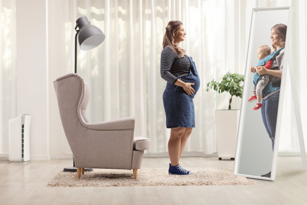 一个孕妇看着镜子里的自己，想象着自己的孩子在家里图片下载