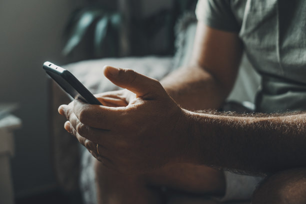 男人用手机写信息或上网搜索的特写镜头。现代人的联系和交流。男性在手家中室内阅读通知或下载app图片下载