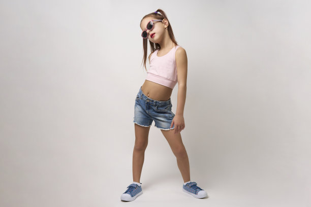 可爱的小女孩穿着牛仔短裤和上衣，白色背景图片下载