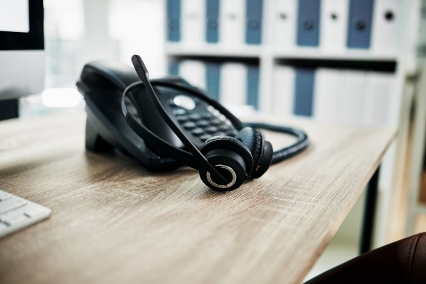 电话，与我们的呼叫中心联系，通讯和耳机与麦克风在工作桌上。联络中心，客户支持和电话，咨询和客户服务与呼叫中心voip。图片下载