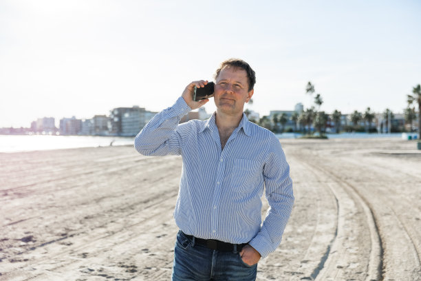 商人打电话，使用智能手机手机应用程序发短信，浏览社交媒体技术，站在城市的现代街道上。图片下载