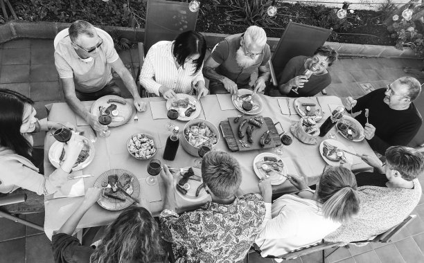 多种族家庭的人吃烧烤晚餐在天井露台-软聚焦在亚洲女人的手-黑白编辑图片下载