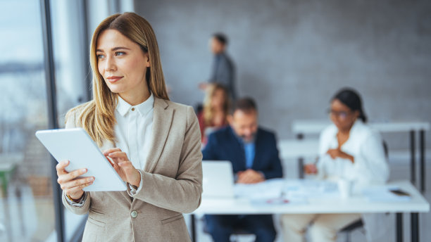 年轻的女商人站在办公室的肖像与一个数字平板电脑。图片下载
