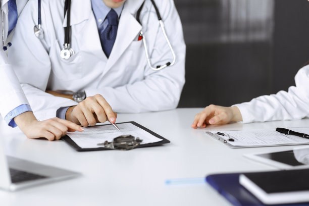 在现代化的医院办公室里，一群不知名的医生坐在桌子前讨论问题或疾病治疗。冠状病毒对抗，病人帮助医学理念图片下载