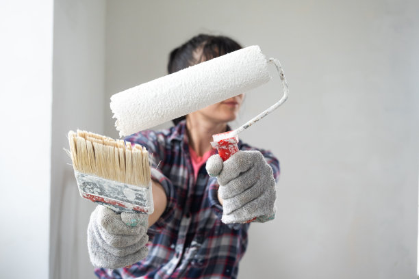 困惑的妇女在油漆辊和白色油漆的墙壁在手中特写肖像。房屋的建筑工作和化妆品维修，墙壁粉刷，着色，亲自完成工作图片下载