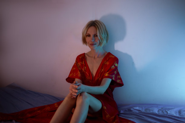 女性的思想，危机。一个穿红外套的女人坐在床上。图片下载