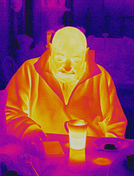 一名秃顶老人在厨房查看手机的红外图像。图片下载