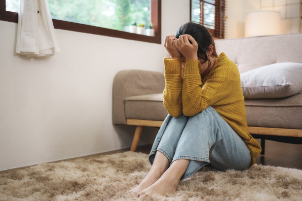 年轻的亚洲女性遭受工作压力独自坐在家里的沙发上气馁。绝望的亚洲女人感到孤独图片下载