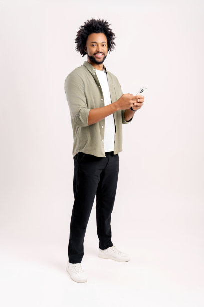 快乐英俊的年轻男人正在使用智能手机发短信，在社交网络中发消息，积极的男人使用移动应用程序，工作室拍摄在白色背景上隔离图片下载