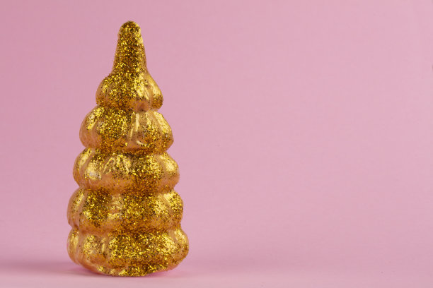 圣诞组成。粉色背景上的金色圣诞树。节日快乐。最小的新年概念。图片下载