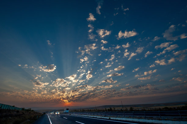 在一个阴天里，初升的太阳和高速公路上的汽车图片下载