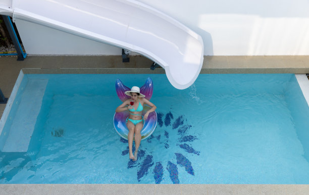 女人在比基尼与橡胶充气浮子。游泳池里穿泳装的女人在游泳管上。美丽的女孩在游泳池从上面，放松游泳充气环。图片下载