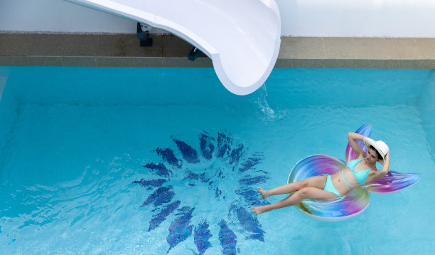 女人在比基尼与橡胶充气浮子。游泳池里穿泳装的女人在游泳管上。美丽的女孩在游泳池从上面，放松游泳充气环。图片下载