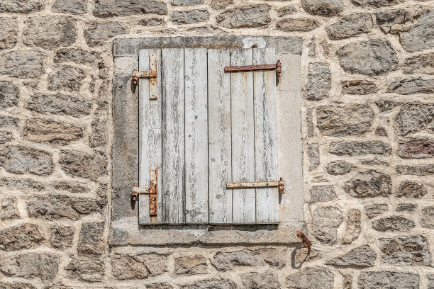黑山布德瓦老城的一堵石墙上，有一扇木制百叶窗和生锈的金属铰链的窗户。古建筑设计元素，特写图片下载