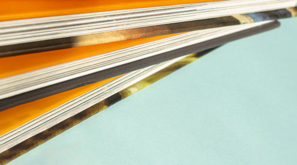 有鲜橙色封面的书。在浅蓝色背景的映衬下，书的明亮封面显得格外醒目。蓝色的背景上放着一堆书。图片下载