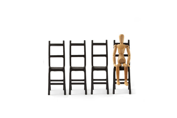 一个木制人体模型坐在白色背景的黑色椅子上。一个人的最低限度的概念是筋疲力尽，疲惫，沮丧，绝望。等待。木偶的姿势。图片下载
