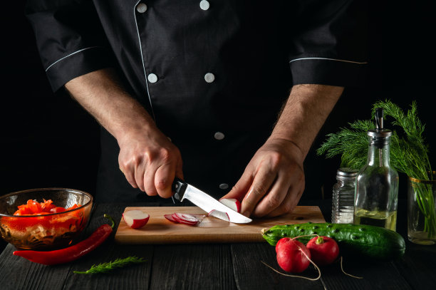 厨师在蔬菜沙拉里切萝卜。在餐厅或咖啡馆的厨房里做美味的沙拉图片下载