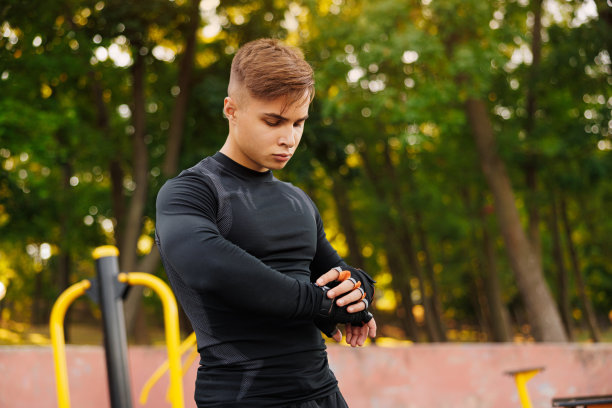 侧面视图年轻强壮运动健身运动员男子20岁在运动服热身训练跑步看智能手表使用应用程序在日出太阳在海边户外码头海滨在夏日早晨。图片下载